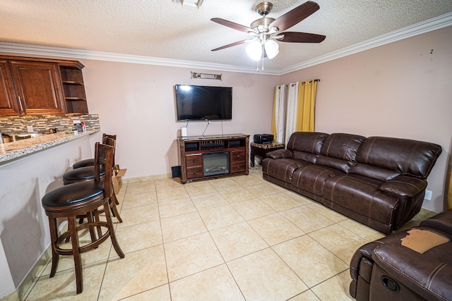 living room featuring ceiling fan, ornamental molding, a textured ceiling, and light tile patterned floors