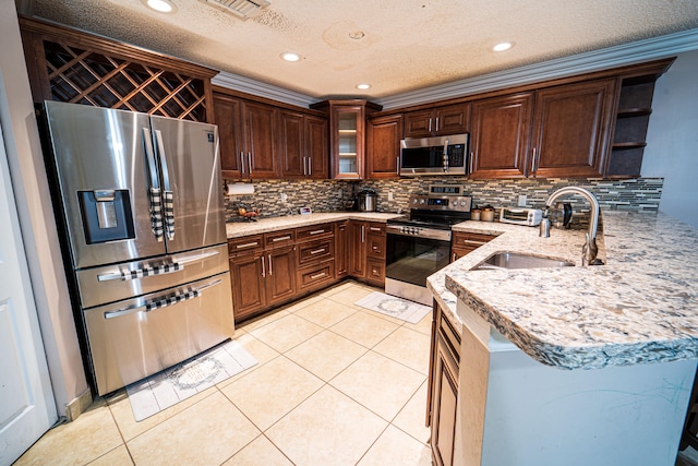 kitchen featuring kitchen peninsula, appliances with stainless steel finishes, a textured ceiling, and sink