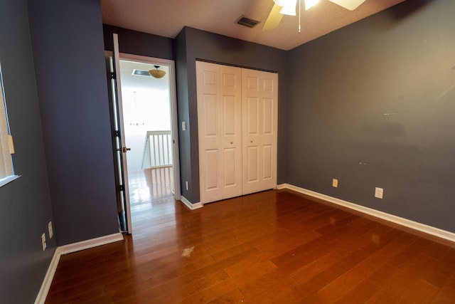 unfurnished bedroom featuring a closet, ceiling fan, dark hardwood / wood-style flooring, and a textured ceiling