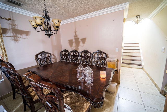 tiled dining space with a chandelier, a textured ceiling, and ornamental molding