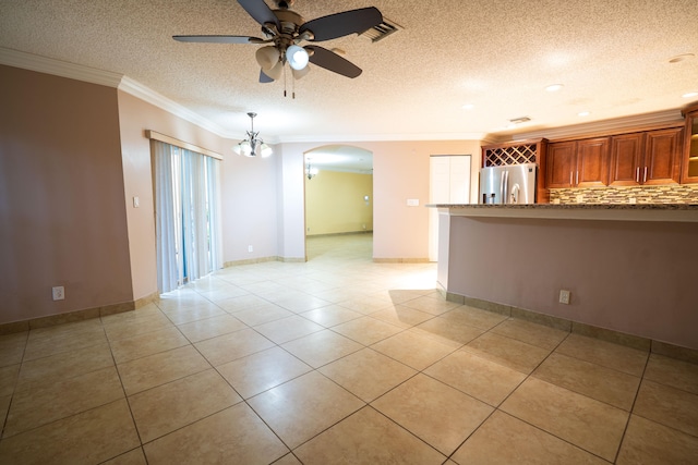 unfurnished room featuring a textured ceiling, light tile patterned flooring, ceiling fan with notable chandelier, and ornamental molding