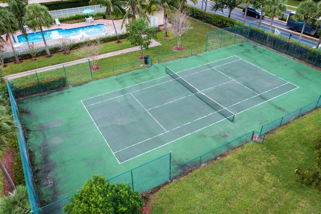 view of tennis court featuring a lawn and a fenced in pool