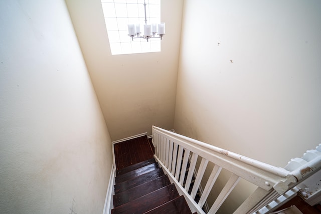 stairway featuring hardwood / wood-style flooring and a chandelier