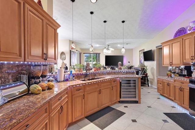 kitchen with pendant lighting, sink, a textured ceiling, and beverage cooler