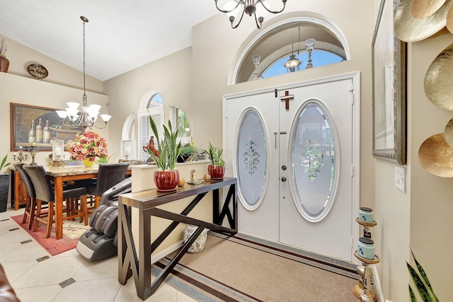 entrance foyer with french doors, light tile patterned flooring, lofted ceiling, and a notable chandelier