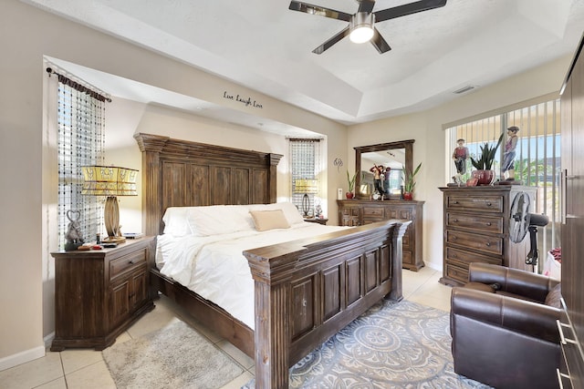 tiled bedroom featuring a raised ceiling and ceiling fan