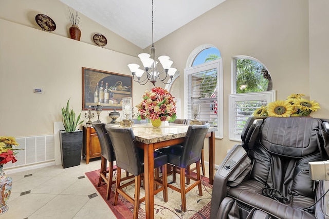 tiled dining space featuring high vaulted ceiling and an inviting chandelier