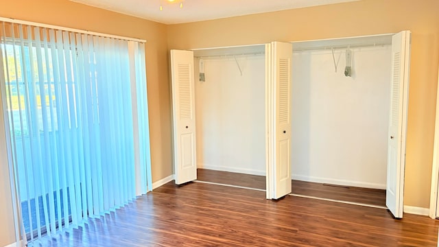 unfurnished bedroom with dark hardwood / wood-style flooring and two closets