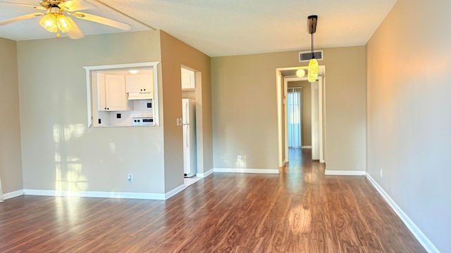 spare room featuring a textured ceiling, ceiling fan, and dark wood-type flooring