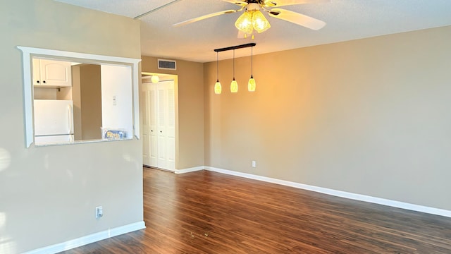 empty room with dark hardwood / wood-style floors, ceiling fan, and a textured ceiling