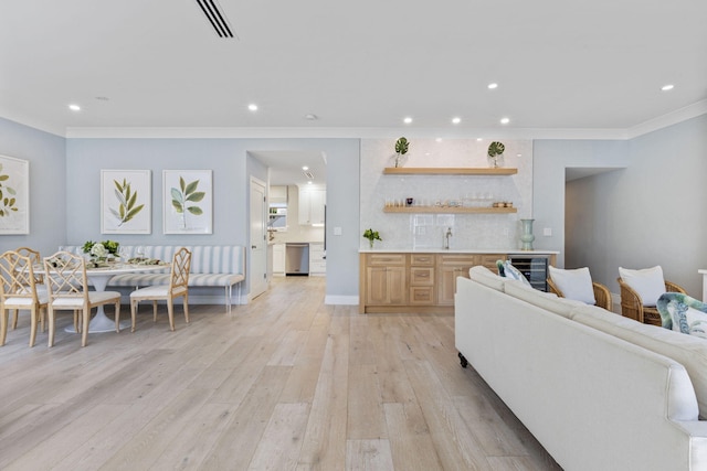 living room featuring wine cooler, light hardwood / wood-style flooring, indoor wet bar, and ornamental molding