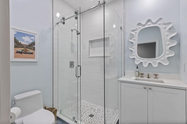 bathroom with vanity, toilet, and a shower with door