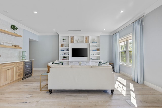 living room featuring wine cooler, crown molding, sink, and light hardwood / wood-style floors