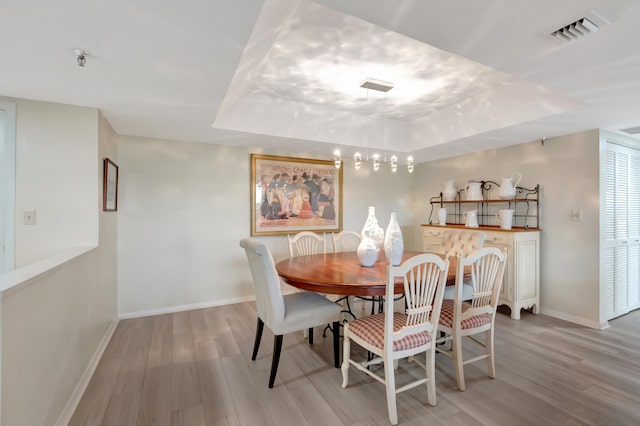 dining space featuring a tray ceiling and light hardwood / wood-style flooring