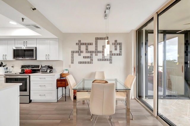 kitchen featuring white cabinets, pendant lighting, light hardwood / wood-style floors, and appliances with stainless steel finishes