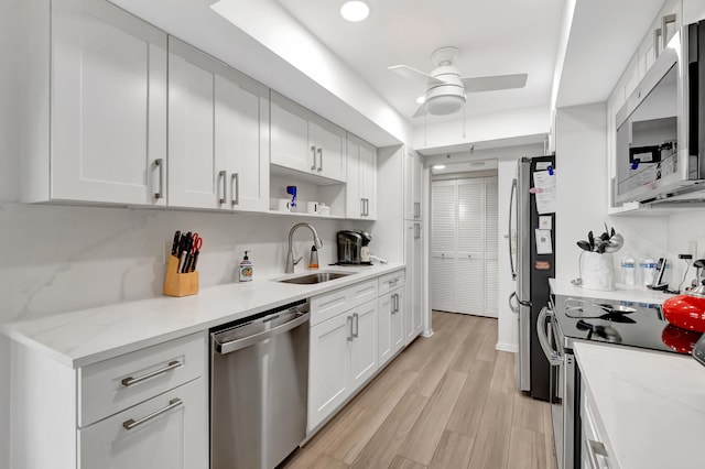 kitchen featuring sink, white cabinets, stainless steel appliances, and light wood-type flooring