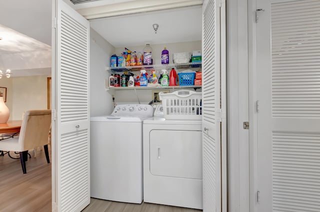 clothes washing area featuring light hardwood / wood-style flooring, washer and dryer, and a notable chandelier