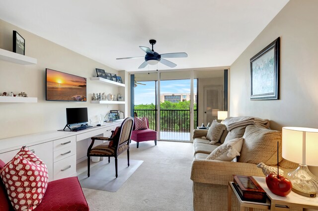 carpeted home office featuring ceiling fan, expansive windows, and built in desk