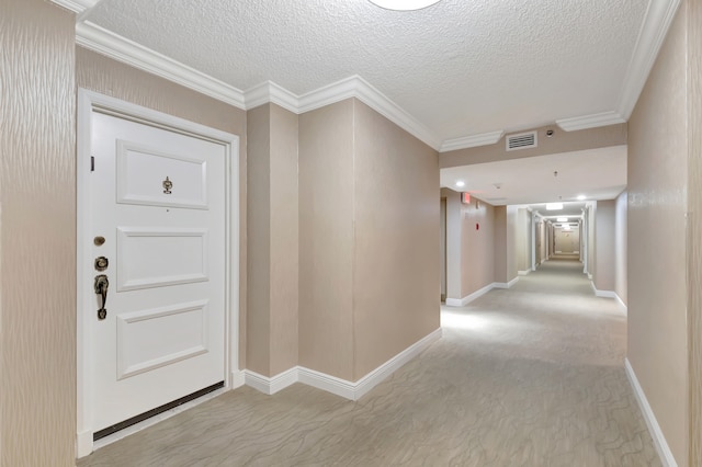 hall featuring light carpet, a textured ceiling, and crown molding