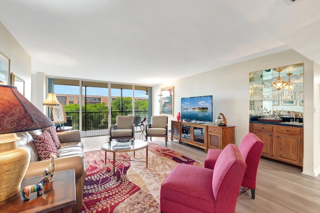 living room featuring light wood-type flooring, a wall of windows, and a notable chandelier