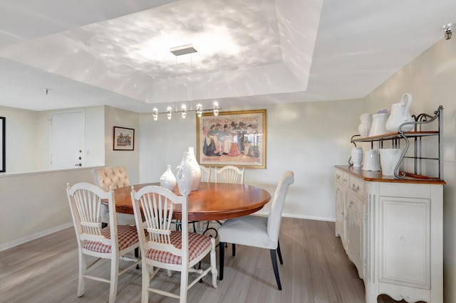 dining space featuring light wood-type flooring and a tray ceiling