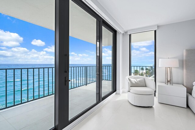 interior space featuring access to outside, a water view, a wall of windows, and light tile patterned flooring