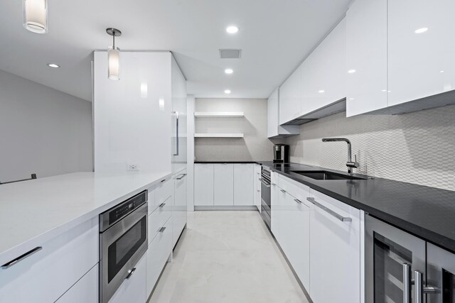 kitchen featuring backsplash, white cabinetry, sink, and decorative light fixtures