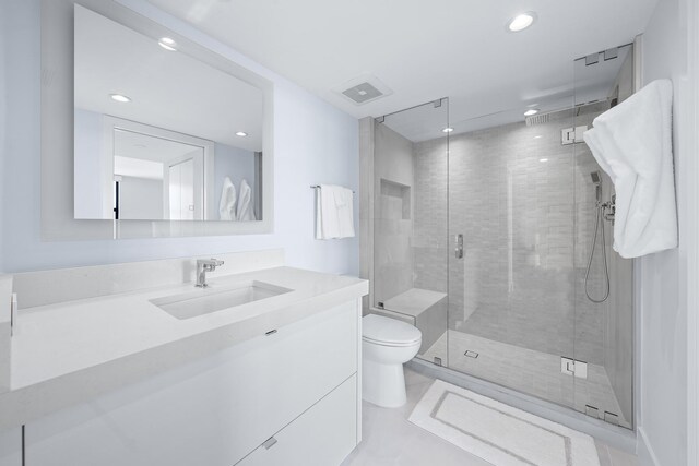 bathroom featuring vanity, toilet, and a shower with shower door