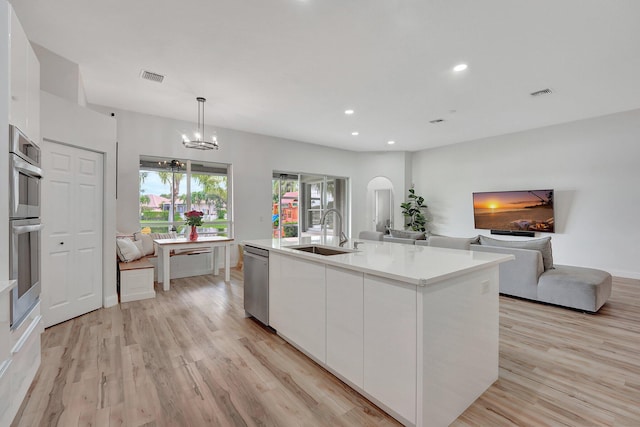 kitchen with stainless steel dishwasher, light hardwood / wood-style floors, white cabinetry, and sink