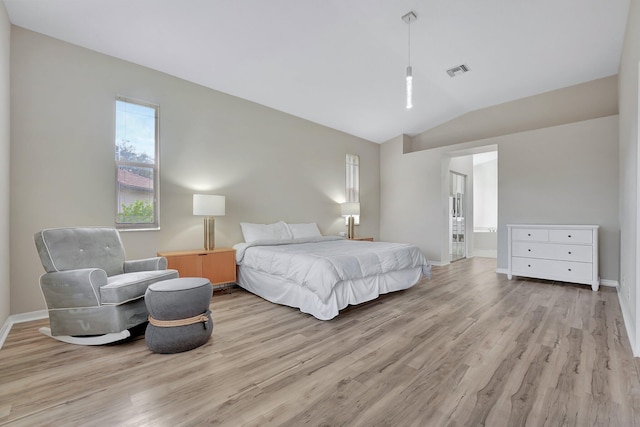 bedroom with light wood-type flooring, vaulted ceiling, and ensuite bathroom