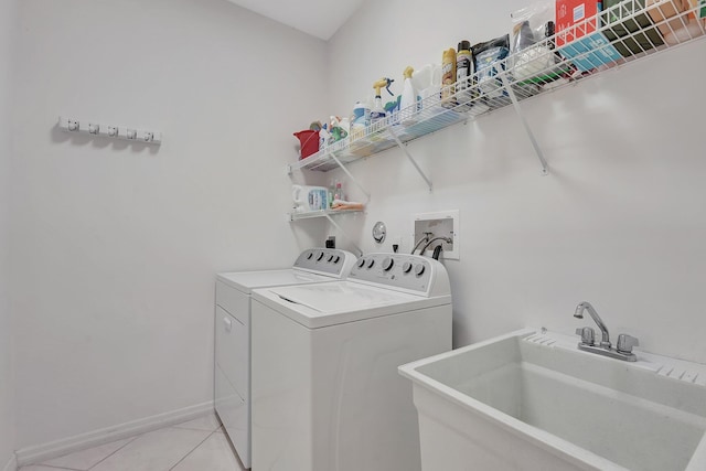 laundry area featuring washing machine and dryer, sink, and light tile patterned flooring