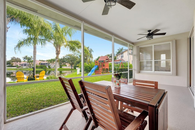 sunroom / solarium featuring a wealth of natural light, ceiling fan, and a water view