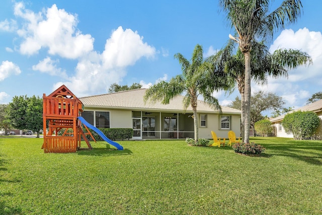 rear view of house featuring a lawn and a playground