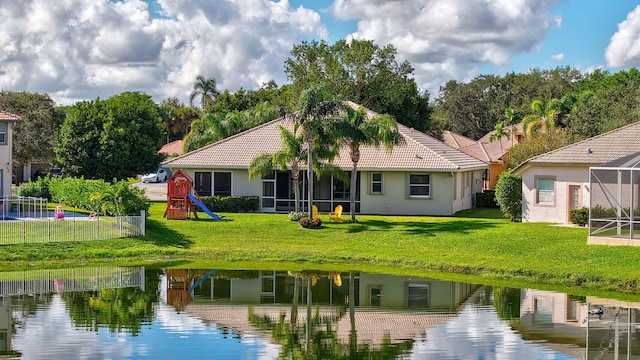 back of house with a playground, a water view, and a lawn