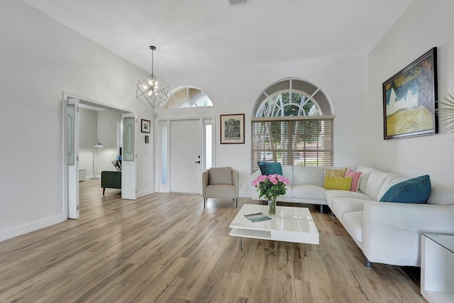 living room with light wood-type flooring, high vaulted ceiling, and a notable chandelier