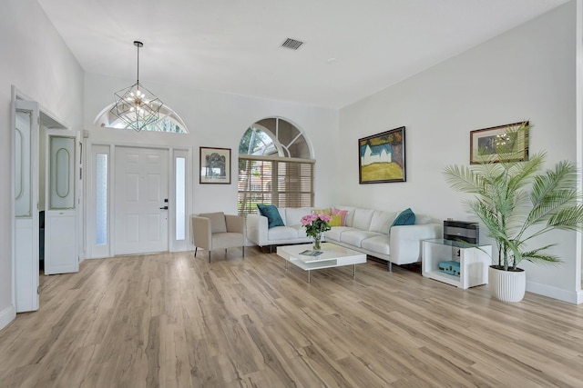 living room with light wood-type flooring, a chandelier, and high vaulted ceiling