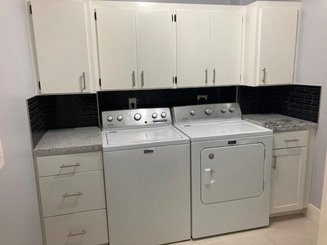 laundry area with cabinets, washer and dryer, and light tile patterned floors