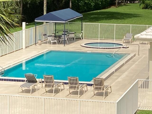 view of pool with a community hot tub, a patio, and a yard