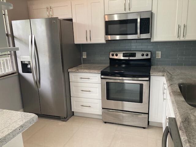 kitchen featuring stainless steel appliances, white cabinetry, and backsplash