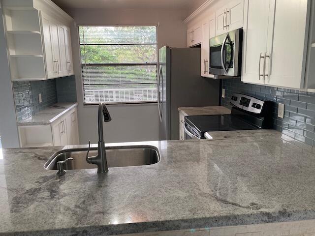 kitchen featuring stainless steel appliances, white cabinetry, and sink