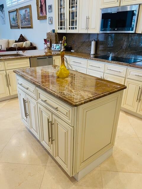 kitchen with a breakfast bar, sink, light stone counters, decorative backsplash, and black electric stovetop