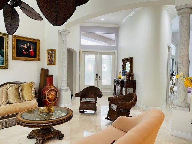 sitting room with french doors, decorative columns, ceiling fan, crown molding, and light tile patterned floors