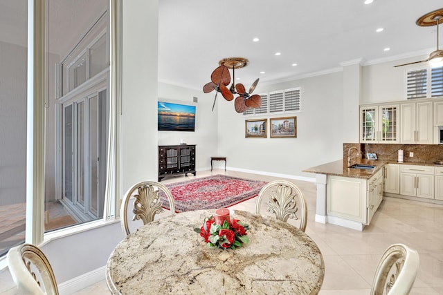 tiled dining space featuring ceiling fan, ornamental molding, and sink