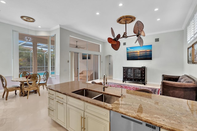 kitchen with light stone counters, cream cabinets, hanging light fixtures, and sink