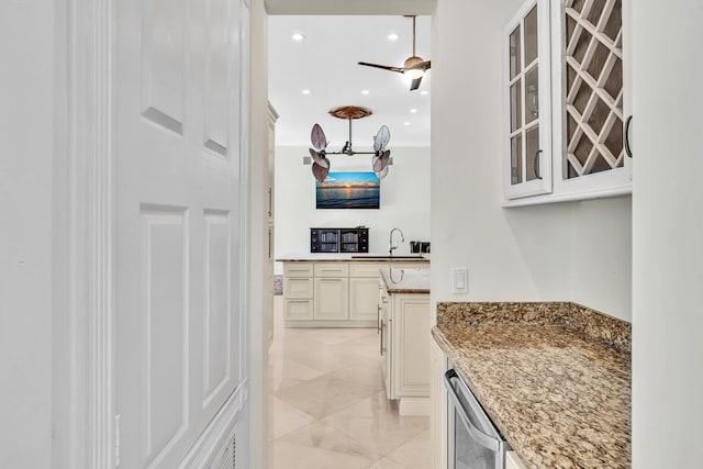 bar featuring cream cabinetry, light stone countertops, ornamental molding, and sink