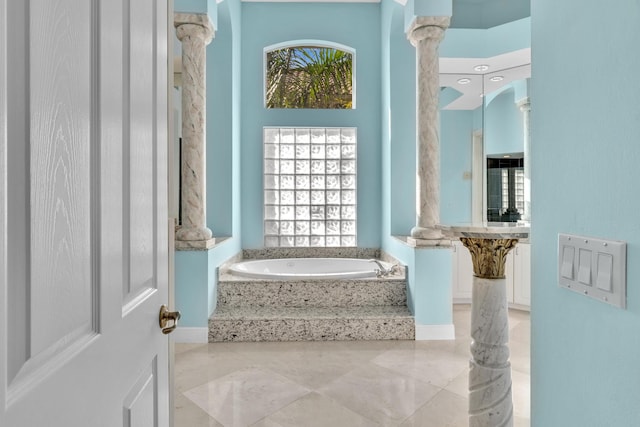 bathroom featuring a relaxing tiled tub and ornate columns