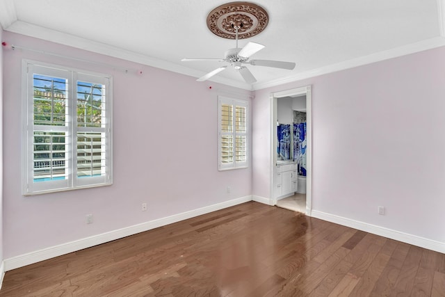 unfurnished bedroom featuring connected bathroom, multiple windows, dark hardwood / wood-style floors, and ornamental molding