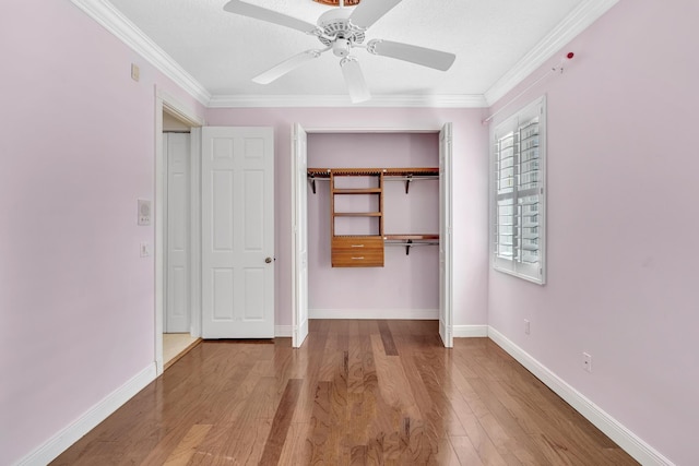 unfurnished bedroom with hardwood / wood-style floors, ceiling fan, crown molding, and a closet