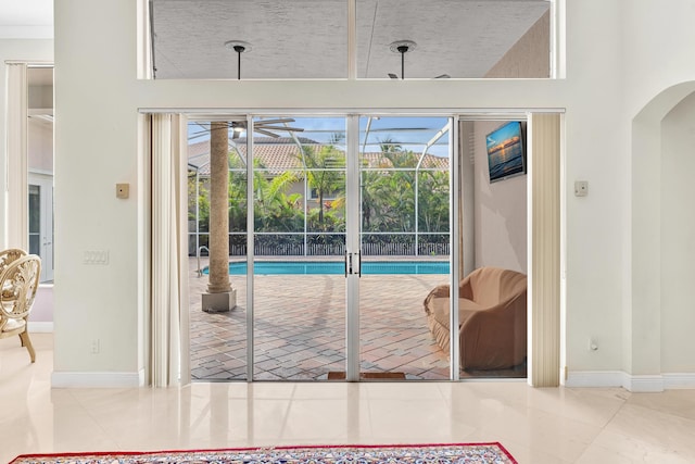 entryway featuring a towering ceiling, tile patterned floors, and a wealth of natural light