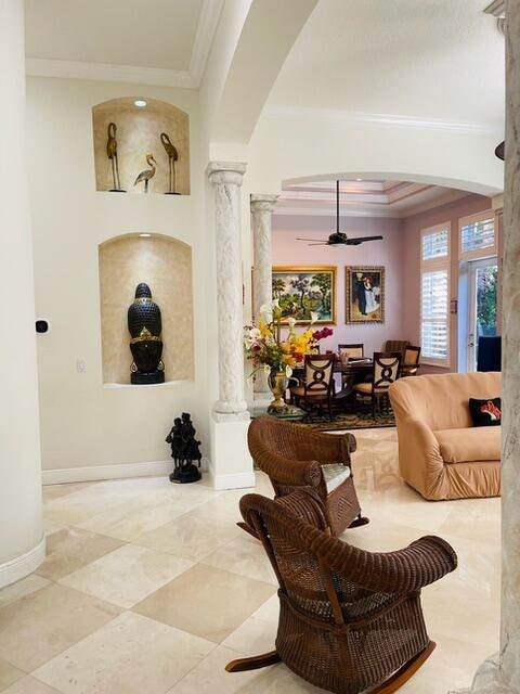 unfurnished living room with ornate columns, crown molding, ceiling fan, and a healthy amount of sunlight